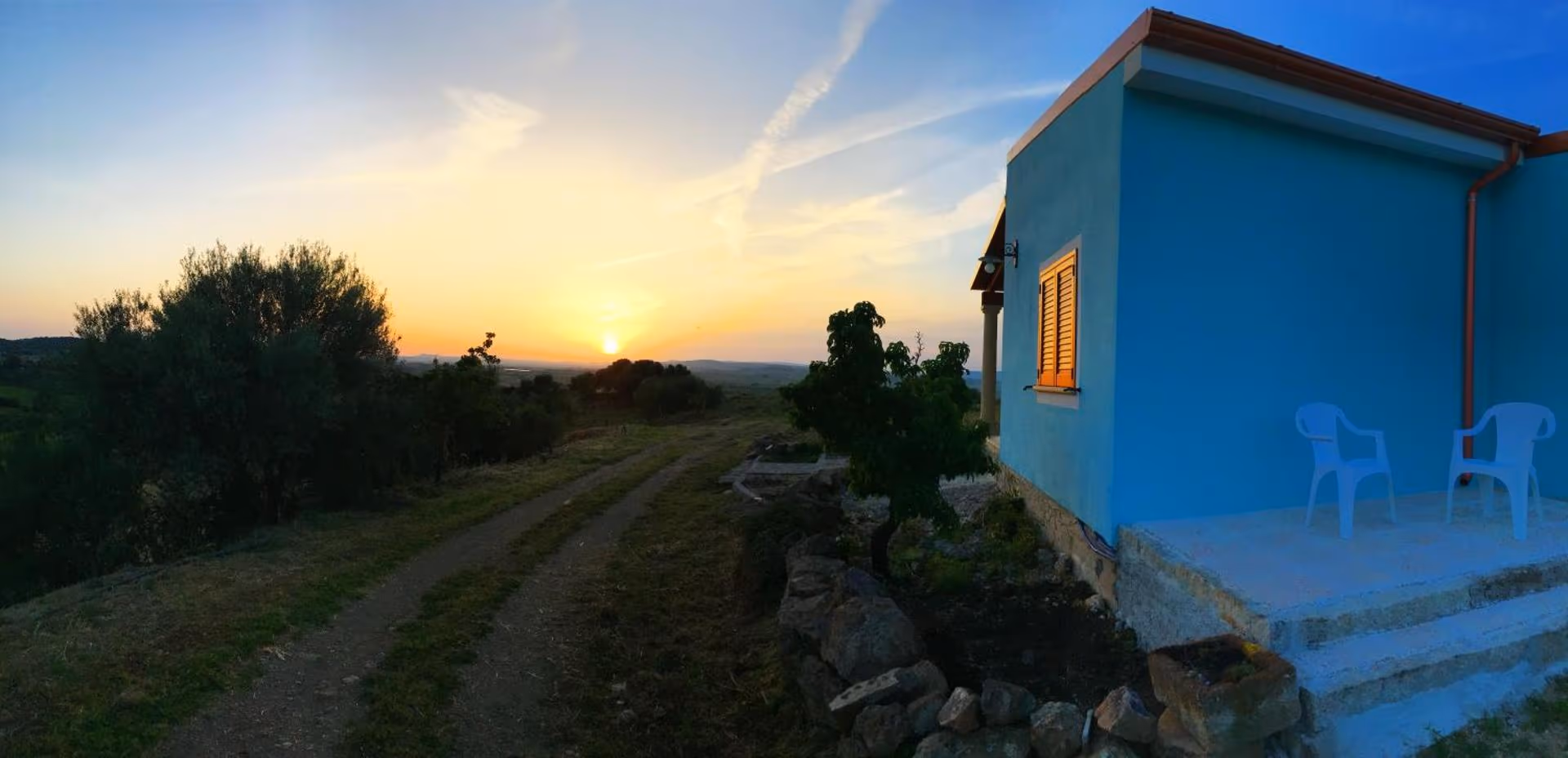 Il cortile al tramonto, con la strada sterrata e la campagna