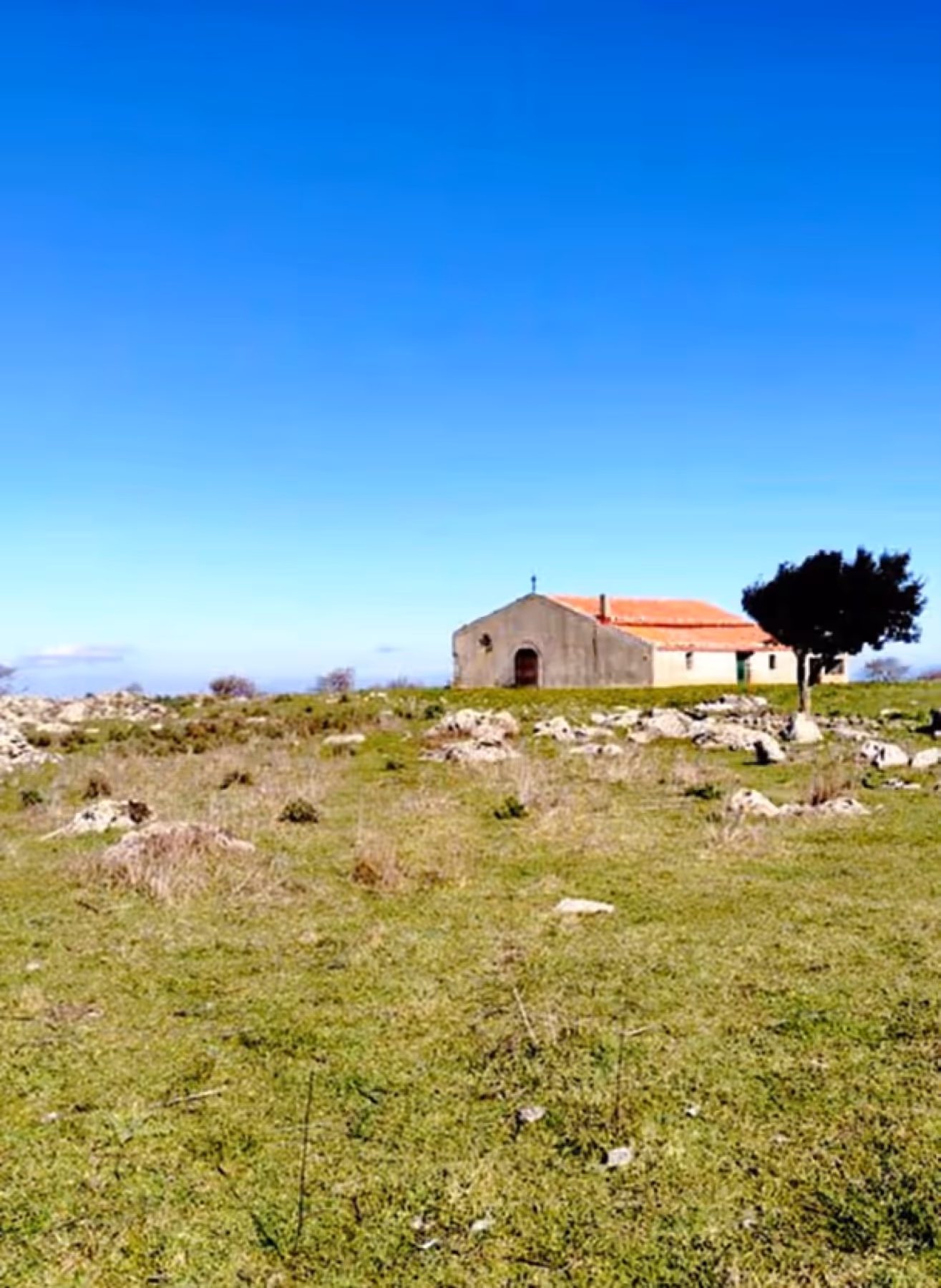 Chiesetta campestre su un altopiano sotto il cielo azzurro