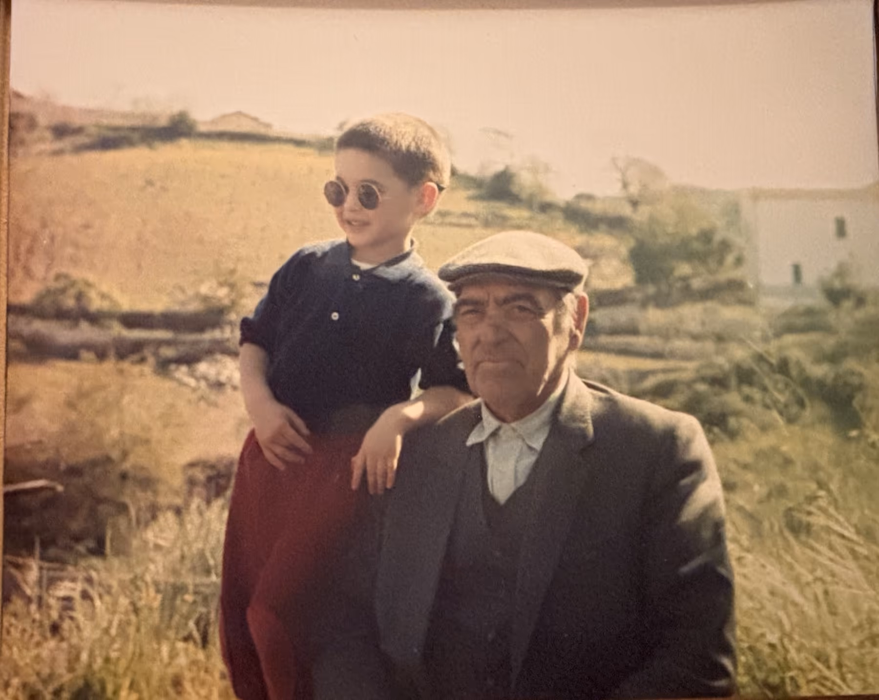 Vecchia fotografia: un uomo anziano con il berretto e un bambino in campagna