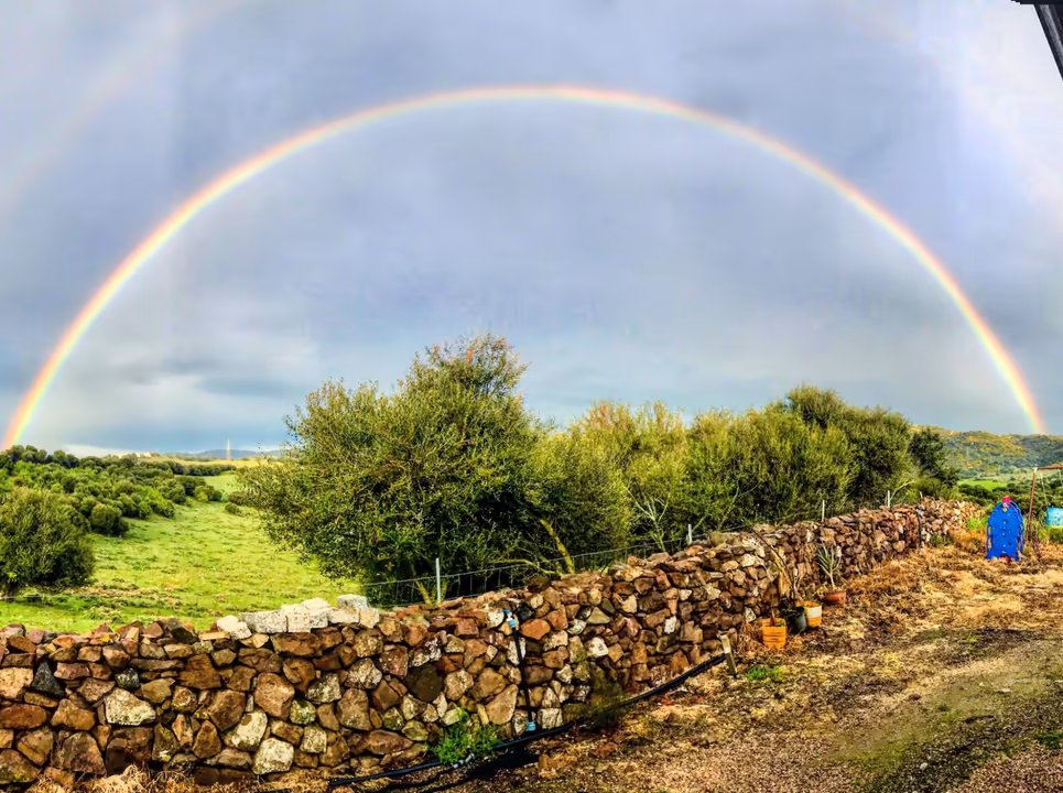 Un arcobaleno sopra la campagna e i muretti a secco